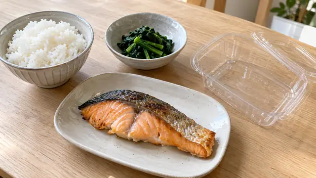 ごはんと主菜・野菜の惣菜を分けて置いた夕食のイメージ。特定店舗の商品や実測の分量を示す写真ではありません